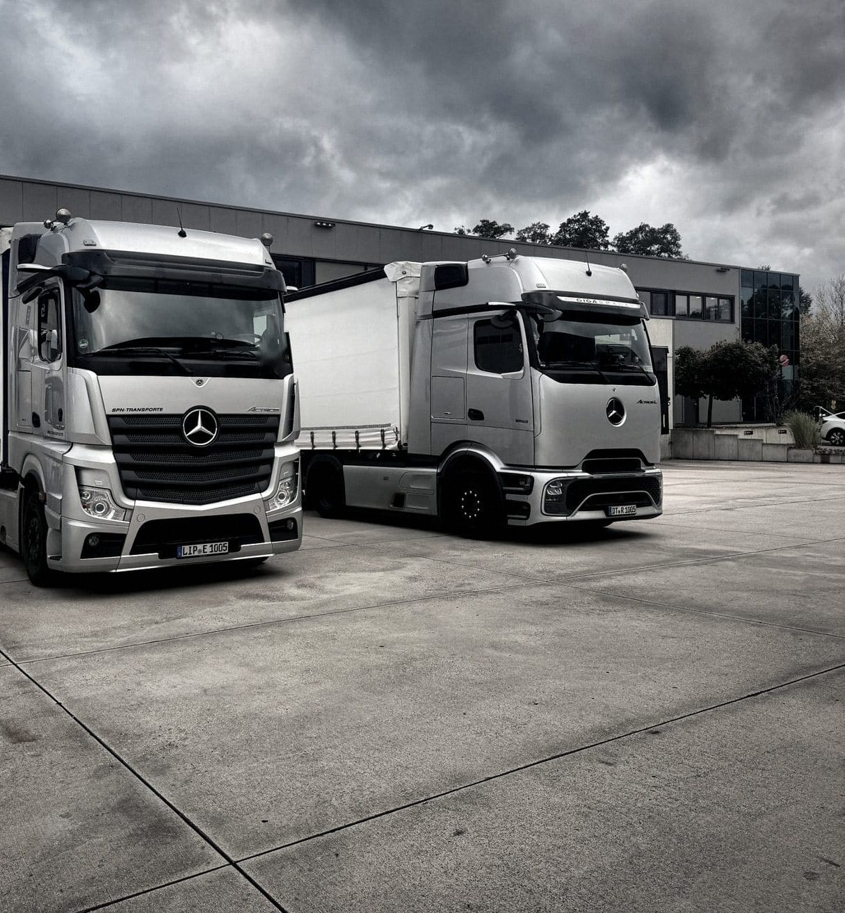 Actros und Actros L mit Planenaufliegern auf dem Hof